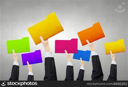 Teamwork and collaboration concept. Group of business people holding folders in raised hands