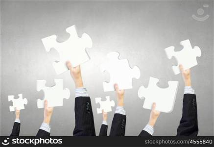Teamwork and cooperation concept. Human hands holding colorful jigsaw puzzle elements
