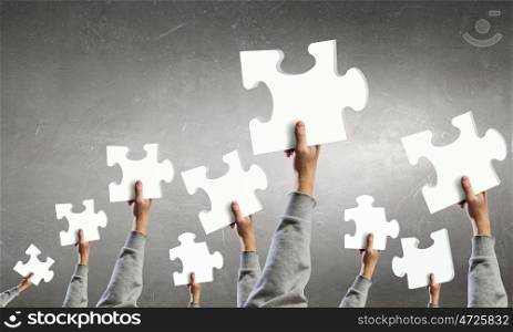 Teamwork and cooperation concept. Human hands holding colorful jigsaw puzzle elements