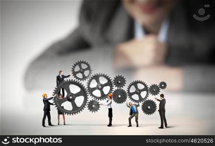 Teamwork concept. Businesswoman looking at team of businesspeople in miniature