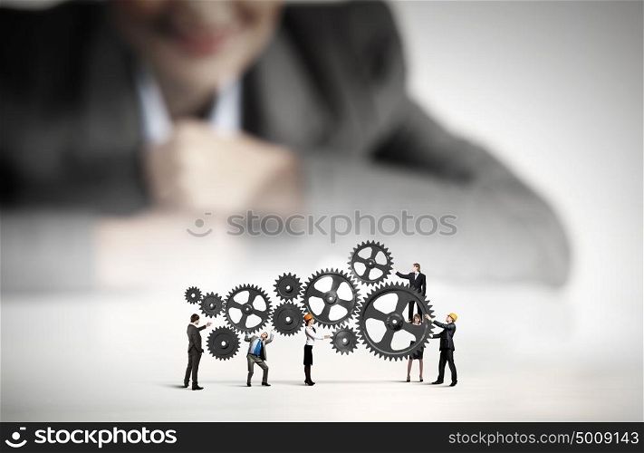Teamwork concept. Businesswoman looking at team of businesspeople in miniature