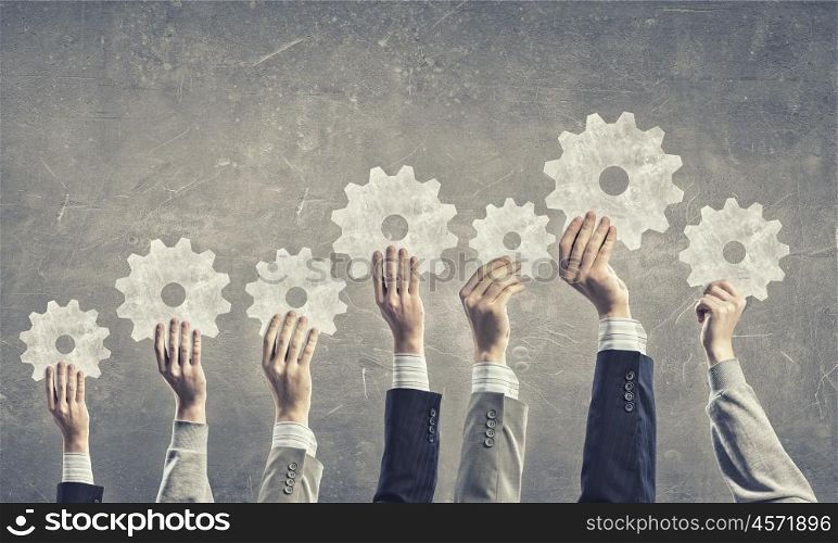 Teamwork concept. Group of business people with raised hands holding cogwheels