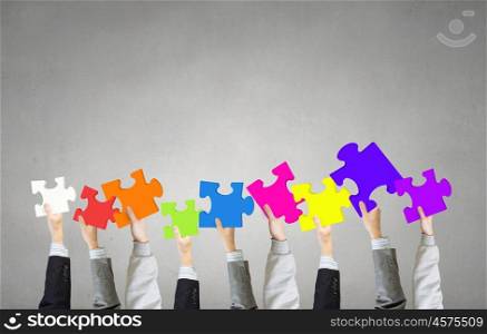 Teamwork concept. Human hands holding colorful jigsaw puzzle elements
