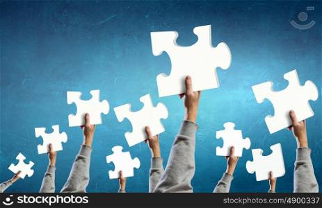 Teamwork concept. Human hands holding colorful jigsaw puzzle elements