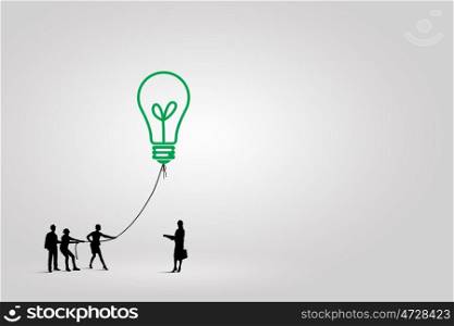 Teamwork concept. Little silhouettes of people pulling light bulb on rope
