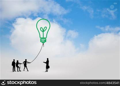 Teamwork concept. Little silhouettes of people pulling light bulb on rope