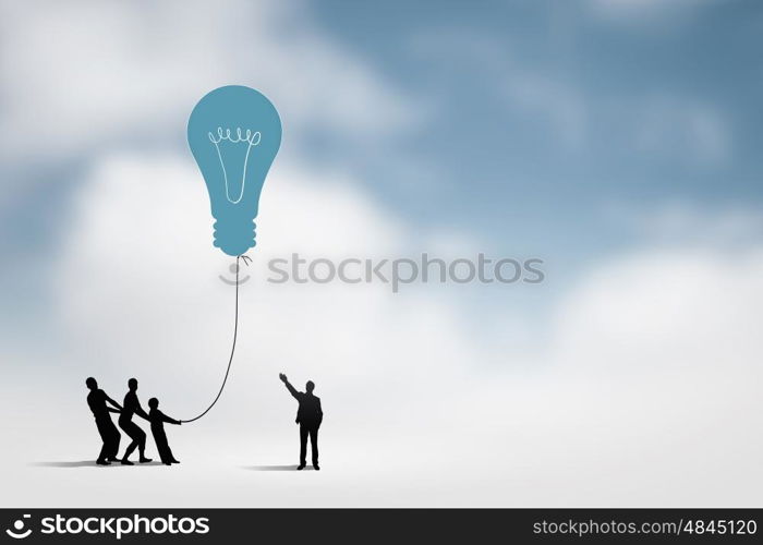 Teamwork concept. Little silhouettes of people pulling light bulb on rope