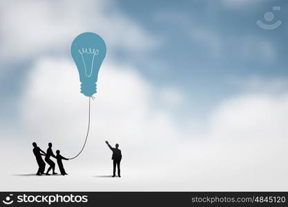 Teamwork concept. Little silhouettes of people pulling light bulb on rope