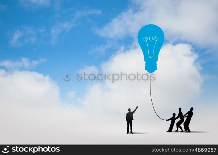 Teamwork concept. Little silhouettes of people pulling light bulb on rope