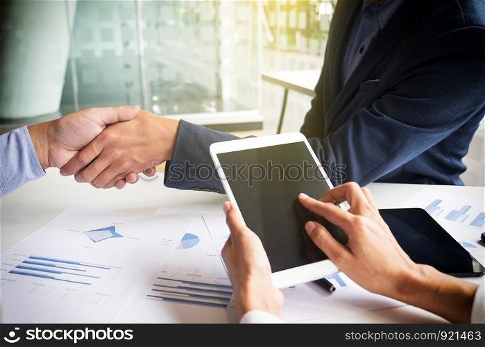 Teamwork concept of office working, Young business men shaking hands with document graph background.