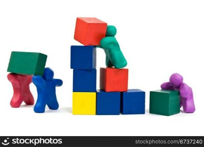 teamwork concept. plasticine people building wooden blocks