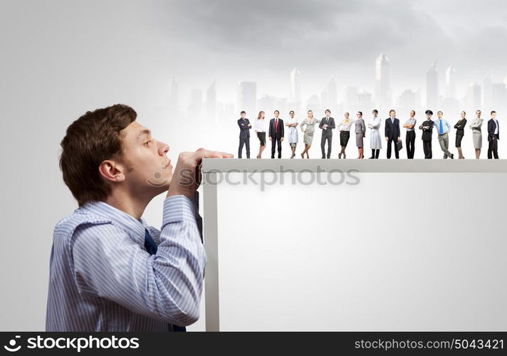 Teamwork concept. Young businessman peeping at people from under table