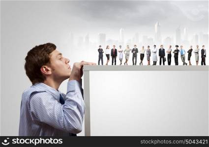 Teamwork concept. Young businessman peeping at people from under table