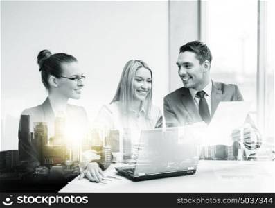 teamwork, corporate, technology and people concept - smiling business team with laptop computer and papers having discussion at office over city buildings and double exposure effect. business team with laptop having meeting at office