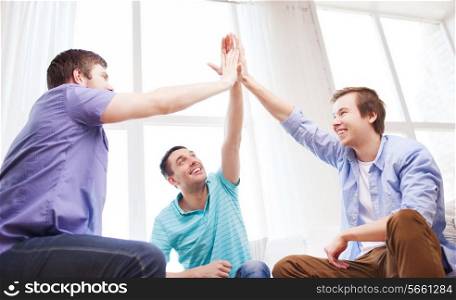 teamwork, friendship and happiness concept - smiling male friends giving high five at home