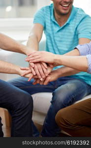 teamwork, friendship, unity, cooperation and gesture concept - close up of happy friends holding hands on top of each other