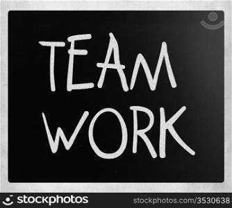 ""Teamwork" handwritten with white chalk on a blackboard."