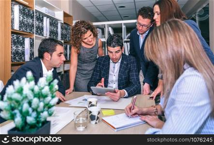 Teamwork looking document in electronic tablet around of business chief in company headquarters. Teamwork looking business document in electronic tablet