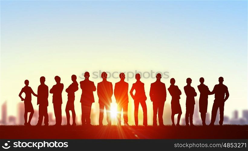 Teamwork on dawn background. Silhouette of business people of different professions on sunset background