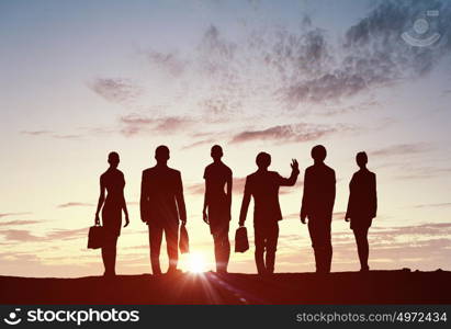 Teamwork on dawn background. Silhouette of business people of different professions on sunset background