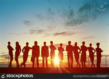 Teamwork on dawn background. Silhouette of business people of different professions on sunset background