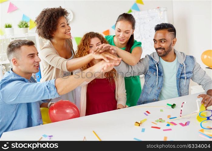 teamwork, success and celebration concept - happy business team holding hands together at office corporate party. happy business team at office party holding hands