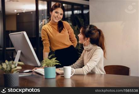 Teamwork, Working Together. Smiling Two Business Woman Workigng on Computer in Modern Office. main model looking at the Camera