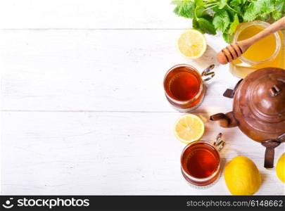 Teapot and cup of tea with mint and lemon on wooden table, top view