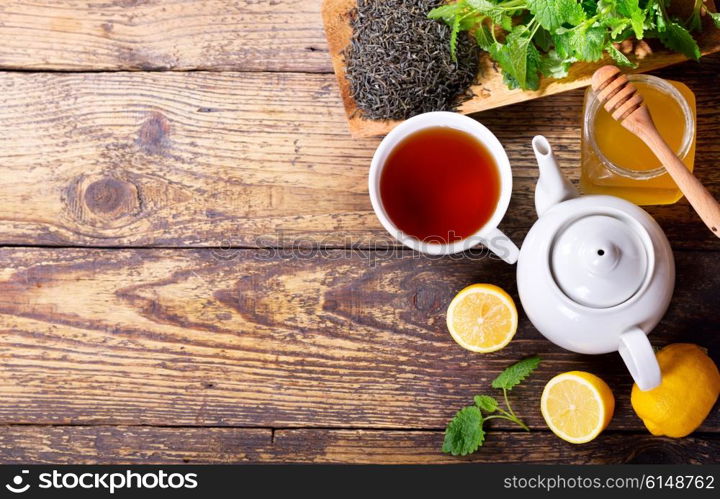 Teapot and cup of tea with mint and lemon on wooden table, top view