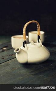 Teapot and cups on wooden background