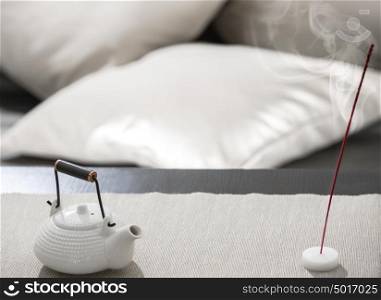 Teapot and incense stick on table at comfortable relaxation lounge