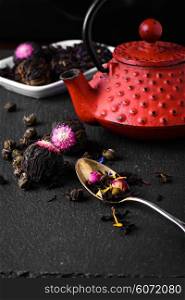 Teapot and loose leaf tea. Red teapot and varieties of loose leaf and blooming tea