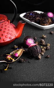 Teapot and loose leaf tea. Red teapot and varieties of loose leaf and blooming tea