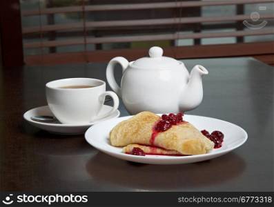teapot, cup of tea and pancakes on plate with sweet cherry confiture