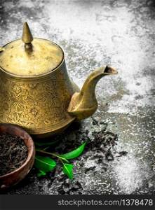 Teapot with black tea. On a rustic background.. Teapot with black tea.