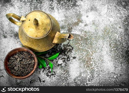 Teapot with black tea. On a rustic background.. Teapot with black tea.