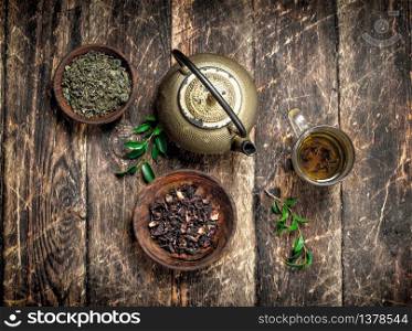 Teapot with green Indian tea. On a wooden background.. Teapot with green Indian tea.