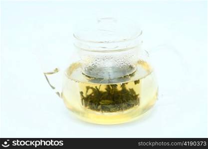 Teapot with green tea on gray background