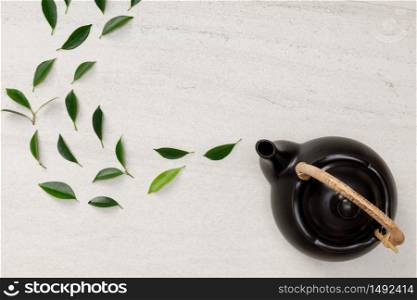 Teapot with organic green tea leaves on the white stone desk empty space creative flat lay, Organic product from the nature for healthy with traditional style