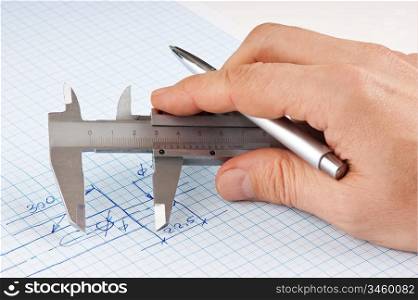 technical drawing and callipers in hand on graph paper