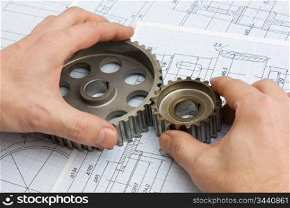 technical drawing and pinion gears in hands