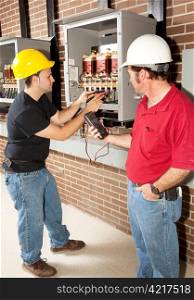 Technical school student learning how to repair industrial power distribution center with the help of an instructor.