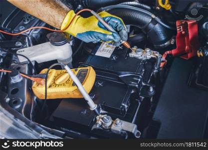 Technician checking DC voltage stable of the car battery with digital multimeter probe