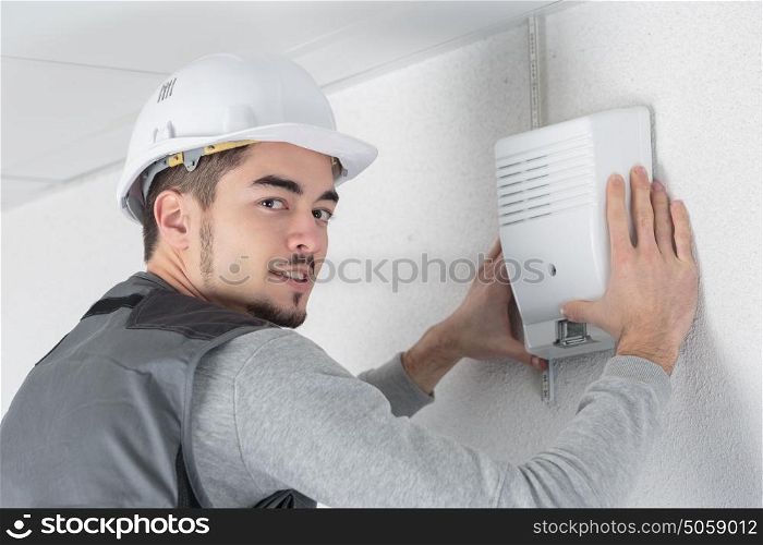 technician checks burglar alarm in professional building