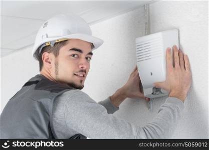 technician checks burglar alarm in professional building
