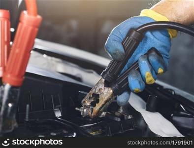 Technician clamping cathode wires jumper to the car battery for recharge