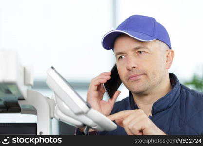 technician getting support over the telephone for programming a photocopier