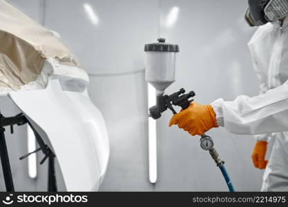 Technician hand in safety clothing spraying paint and varnish on car body part. Car painting. Technician in safety clothing spraying car paint
