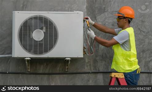 Technician is checking air conditioner . Technician is checking outdoor air conditioner unit