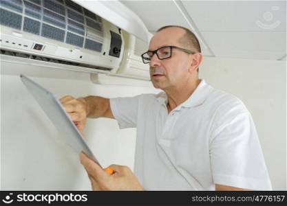 technician repairing air conditioner on the wall